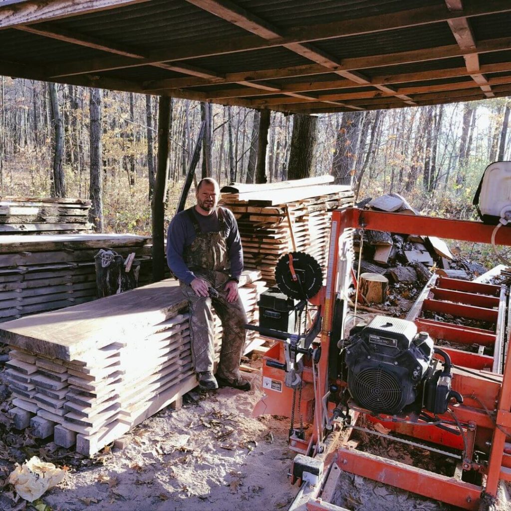 New bar owner sits by Woodmizer saw mill getting ready to plane log for Chicago taproom