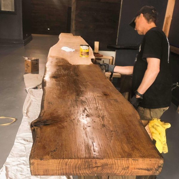 Man staining live edge bar in new Chicago taproom