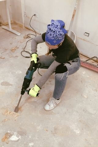 Girl in bandana takes jackhammer tool to cement floors