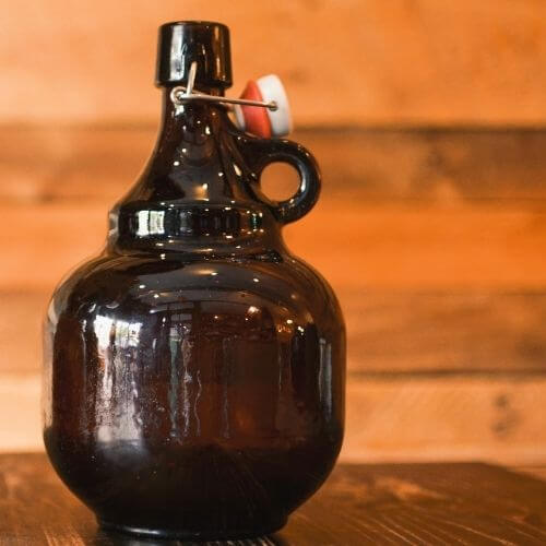 Beer growler on a wood table with wood paneled wall in the background